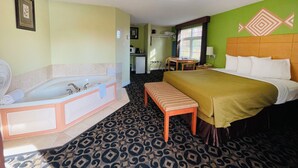A hotel room with a large bed, a separate bathroom with a bathtub, a small table, and a chair. - North Bay Inn (North Bay)