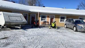 A snow-covered parking lot with a trailer, a red motorcycle, and a yellow snowmobile. - North Bay Inn (North Bay)