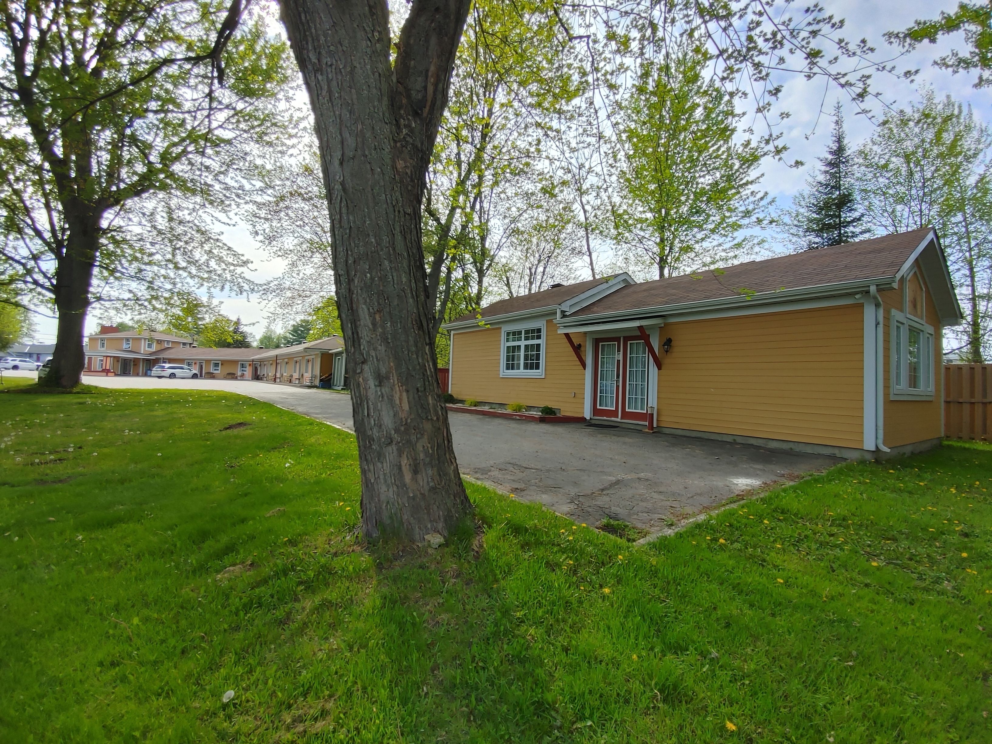 A single-story building with a red door and white trim, surrounded by a well-maintained lawn and trees.