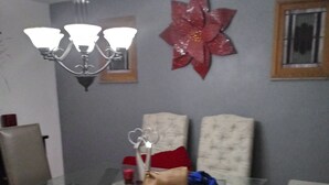 Ein Essbereich mit Glastisch, zwei Stühlen, einer Bank, einer Chandelüster und einem Wandkunstwerk.
