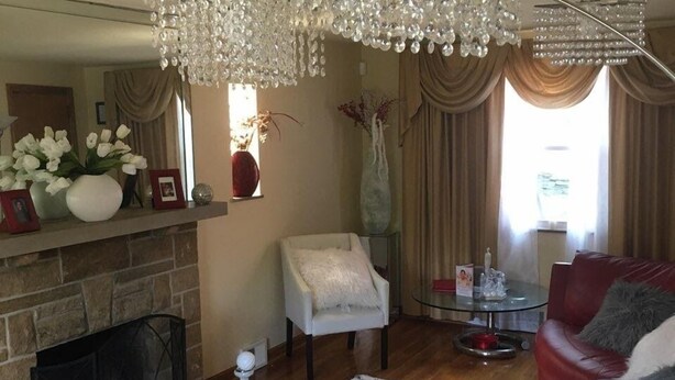 Ein Wohnzimmer mit Kamin, einem roten Ledersofa, einem Glastisch und einer Chandelier.