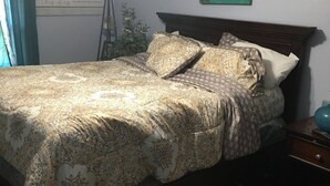 Ein Schlafzimmer mit Bett, Nachttisch, Lampe und Deckenventilator.