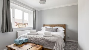 Une chambre à coucher avec un lit, deux serviettes, un banc en bois et une fenêtre avec des rideaux.