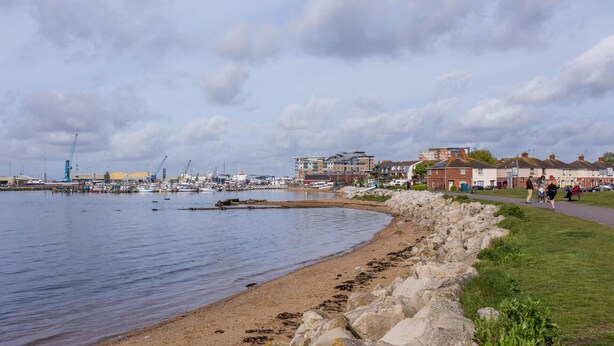 Une ville côtière dotée d’un port de plaisance, d’une côte rocheuse et d’immeubles d’habitation.