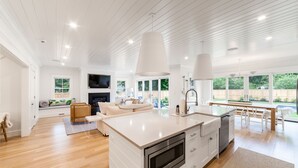 Una cocina moderna con una isla grande, muebles blancos y un horno empotrado.