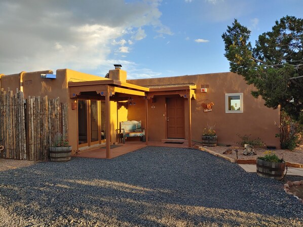 A rustic building with a covered patio, a wooden fence, and a gravel driveway. - Dark Sky Retreat Near Santa Fe (Santa Fe)