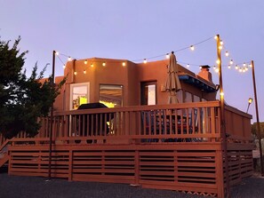 A wooden deck with string lights, a covered patio area, and a building with a chimney. - Dark Sky Retreat Near Santa Fe (Santa Fe)