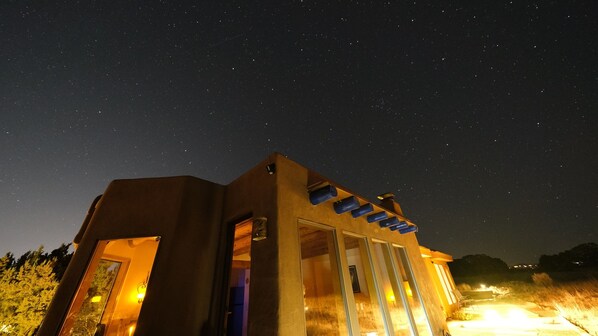 Un edificio moderno con un amplio ventanal y ventanas, frente a un cielo estrellado.