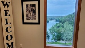 Une pièce dotée d’une grande fenêtre donnant sur un paysage magnifique, d’une photographie encadrée accrochée au mur et d’une pancarte sur laquelle on peut lire « BIENVENUE ».