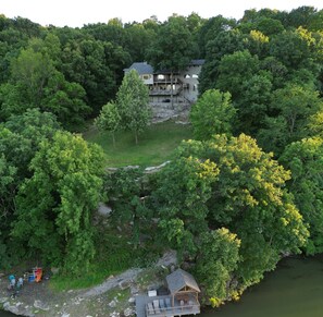 Overlooking the serene lake, this two-story house offers a peaceful retreat surrounded by lush greenery and a dock area.