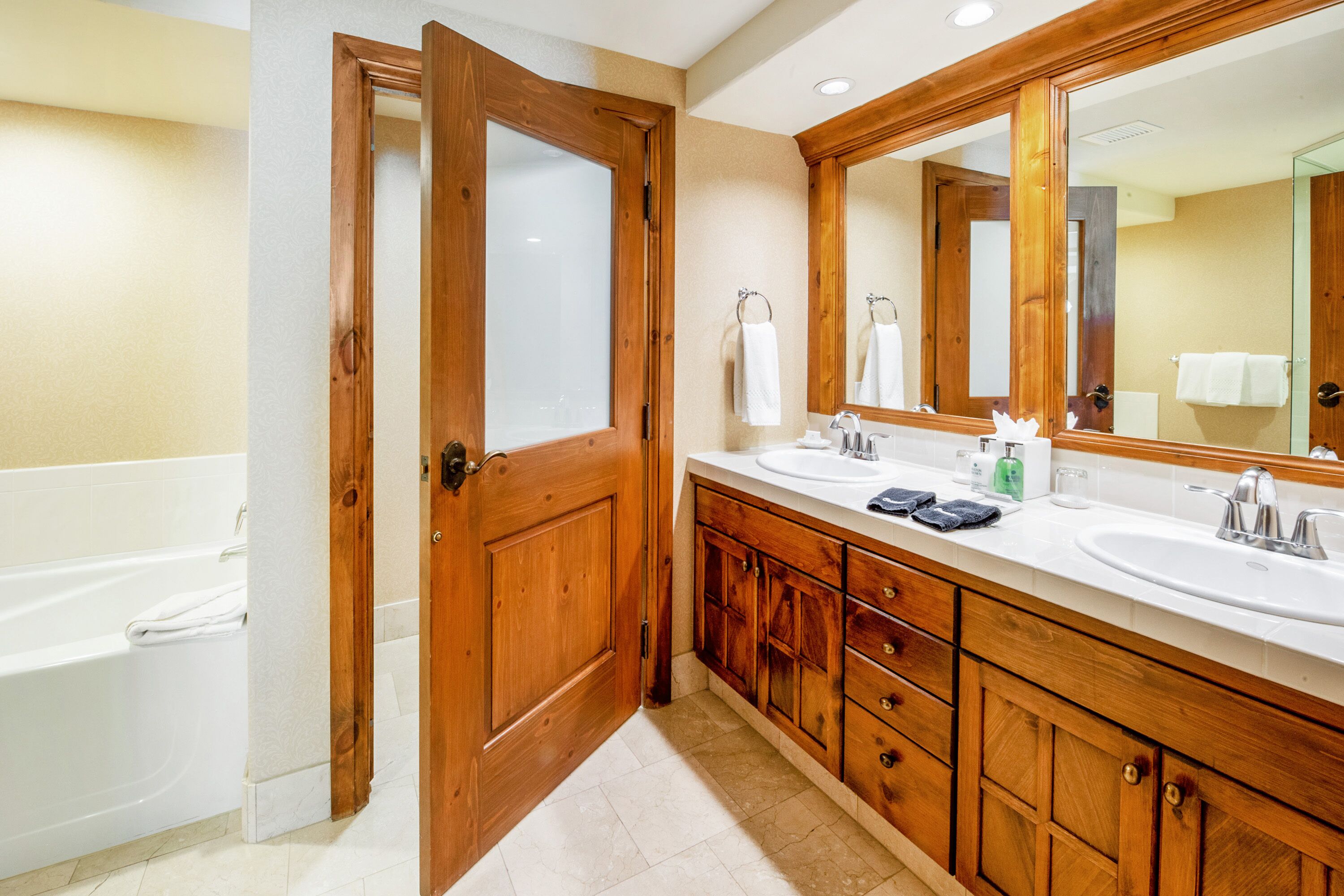 Une salle de bain avec des meubles en bois, un double vasque et un grand miroir.