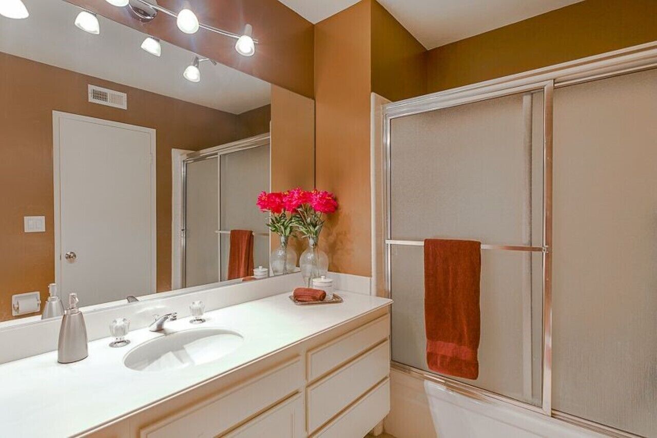 A bathroom with a white vanity, a large mirror, and a shower enclosure.