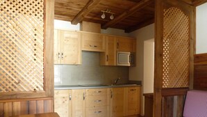 A wooden cabin interior with a kitchen area, including cabinets, a microwave, and a dining table with a floral centerpiece. - Alpen Suite- New vacation apartment in a fantastic location with stunning panoramic views (Trentino - Alto Adige)