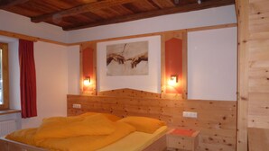 A wooden bed with a headboard, a nightstand, and a wall-mounted artwork. - Alpen Suite- New vacation apartment in a fantastic location with stunning panoramic views (Trentino - Alto Adige)