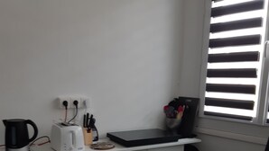 Eine kleine Küche mit Toaster, Wasserkocher und einem Fenster mit Jalousien.