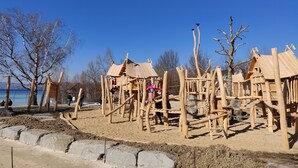 A playground with wooden climbing structures and a sandy ground. - Small 3-room apartment with large terrace, 150m to the lake (Uhldingen-Mühlhofen)