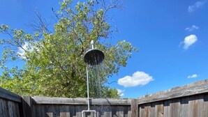 A wooden fenced outdoor area with a metal showerhead. - Cozy Rustic Cabins for Self or Family Retreat (Whitewright)