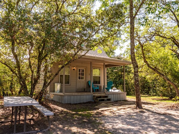 A small cabin with a porch, two chairs, and a table.