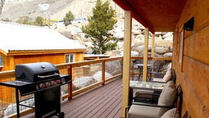 Una terrazza esterna coperta con barbecue, zona relax e vista su un paesaggio montuoso.