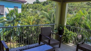 A balcony with a wicker chair, a small table, and a potted plant. - Water Mills Beach Apartments (Ocho Rios)