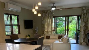 A spacious living area with a central island, a dining table, and a sofa. - Water Mills Beach Apartments (Ocho Rios)