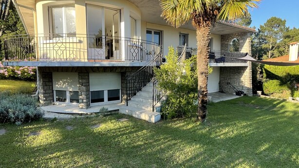 A two-story house with a balcony, a stone facade, and a well-maintained lawn. - Superbe Villa Familiale (Tarnos)