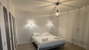 A bedroom with a bed, a ceiling fan, and a window with curtains. - Superbe Villa Familiale (Tarnos)