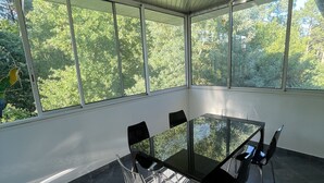 A modern meeting room with a glass table and chairs, large windows, and a view of trees. - Superbe Villa Familiale (Tarnos)