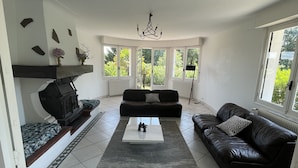A modern living room with a black leather sofa, a white coffee table, and a patterned rug. - Superbe Villa Familiale (Tarnos)
