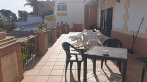 Een terras met een tafel en stoelen, een kleine tafel met een kopje, en een bezem.