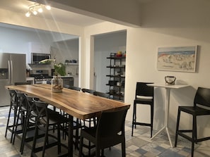 Cozinha moderna com mesa de jantar de madeira, cadeiras e ilha. Dá para ver um micro-ondas, forno e pia.