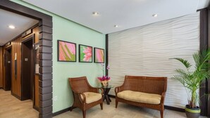 Ein Empfangsbereich mit zwei Korbschaukeln, einem kleinen Tisch mit Blumenvase und einer Wand mit drei gerahmten floralen Bildern.