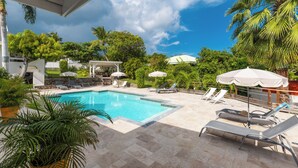 A pool area with lounge chairs, umbrellas, and a clear blue sky.