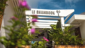 The exterior of Le Shamrock with a clear sky and lush greenery.