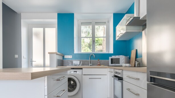 A modern kitchen with a washing machine, microwave, and stainless steel appliances. - Le Cancalais - Port - Wifi - Plage (Cancale)