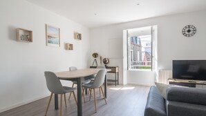 A modern living room with a sofa, a dining table with chairs, a TV, and a balcony with a view. - Le Cancalais - Port - Wifi - Plage (Cancale)