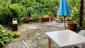 Ein Patio mit Steinböden, einem Tisch, Stühlen und Topfpflanzen.