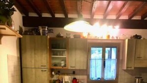 Eine Küche mit Holzausstattung, einem Esstisch mit Stühlen und einem Fenster mit Vorhängen.