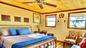 Un dormitorio con cama, una silla, un escritorio y una ventana.