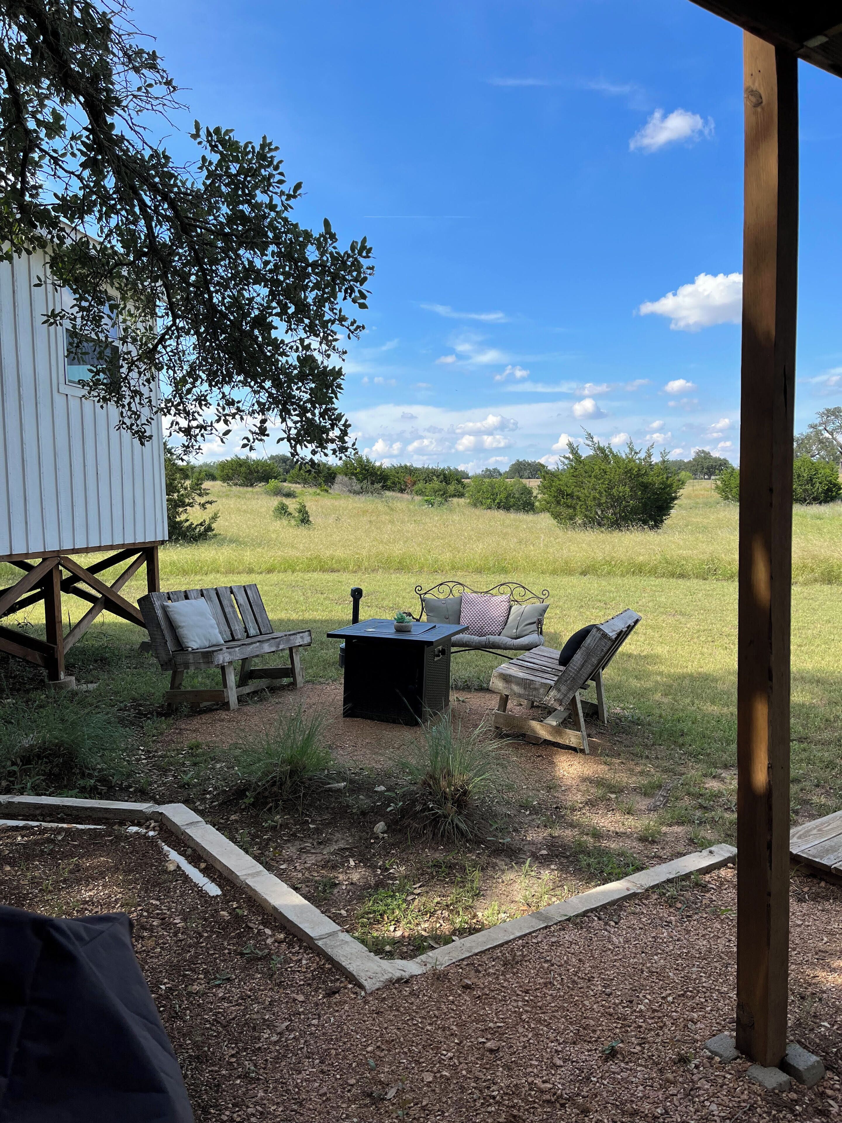 Un espace extérieur abrité, aménagé avec une table, des chaises et un petit jardin.