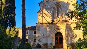 Un bâtiment en pierre doté d’un clocher, d’une entrée en arc de cercle et de plantes en pot.