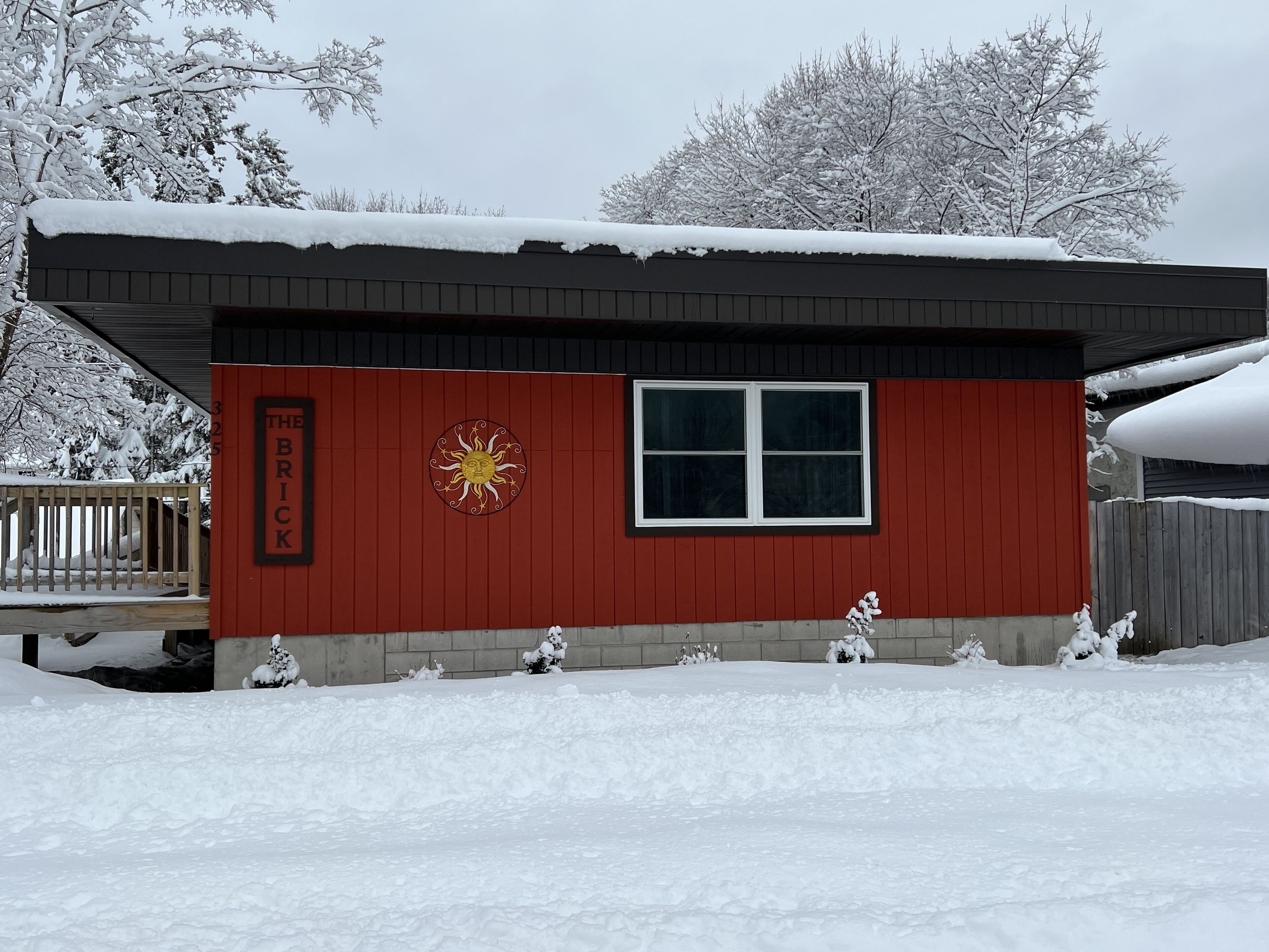 A red building with a large window and a sun emblem on the side.