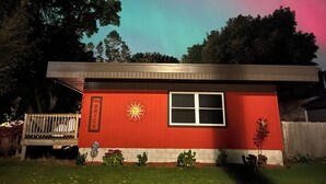 A red house with a solar emblem, a window, and a bench in front.
