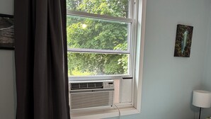 A room with a window, an air conditioner, a lamp, and a power outlet.