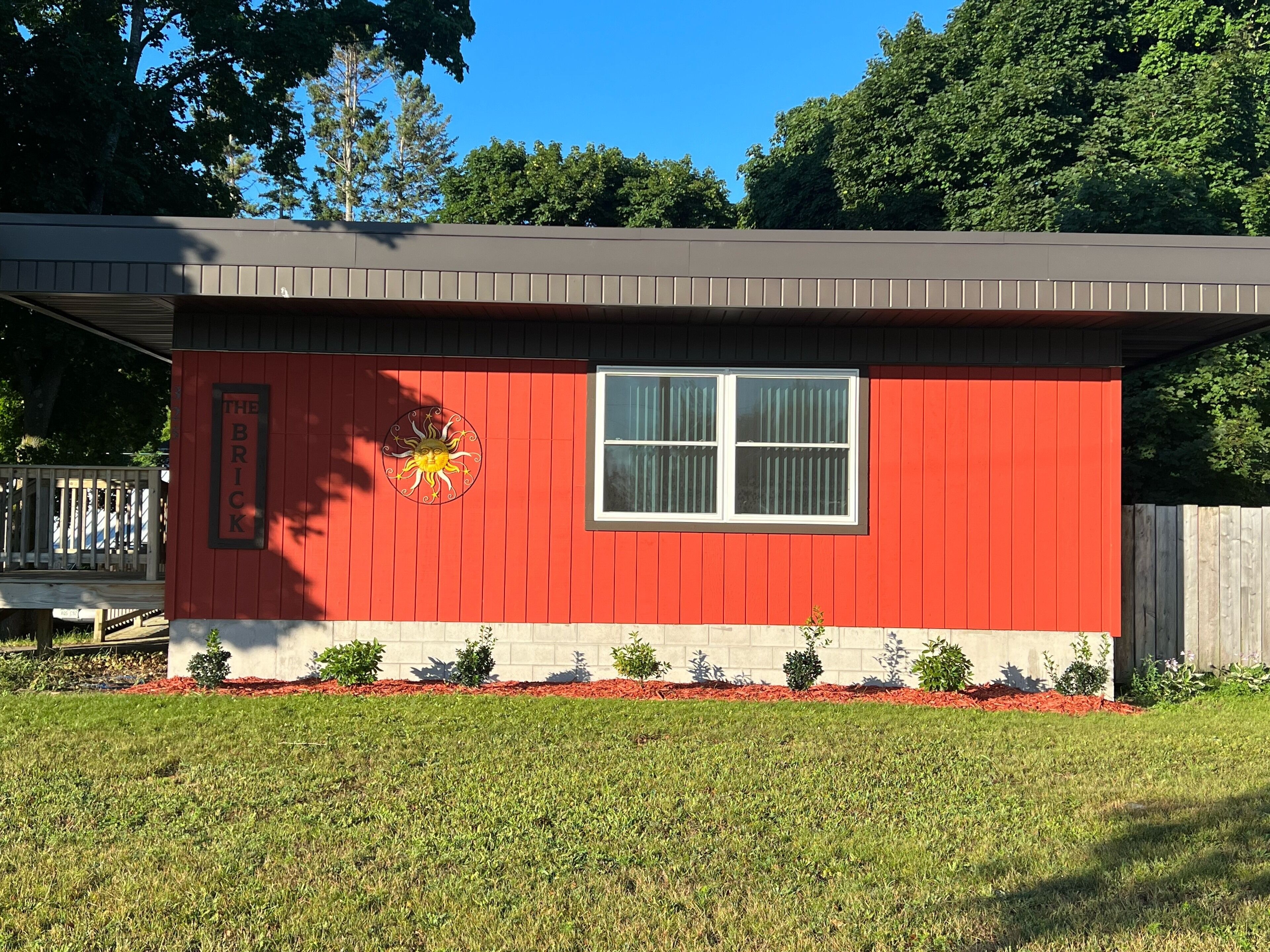 A red building with a white window and a sun mural on the side.