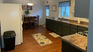 A kitchen with wooden cabinets, a countertop, a sink, and a stove.