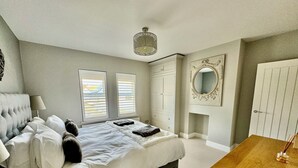 A bedroom with a bed, bedside tables, a dresser, a mirror, and a wooden nightstand. - Ashburn, holiday home close to the beach (Seaview)