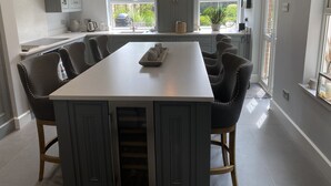 A modern kitchen with a central island, dark upholstered chairs, and a pendant light. - Ashburn, holiday home close to the beach (Seaview)