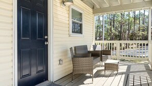 A porch with wicker furniture and a black door.