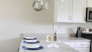 A kitchen with a granite countertop, a hanging pendant light, and a white cabinet.